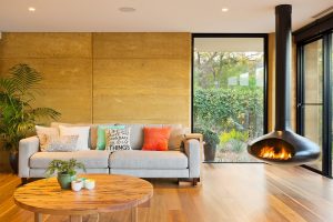 Internal rammed earth feature wall in modern living room with floating fireplace